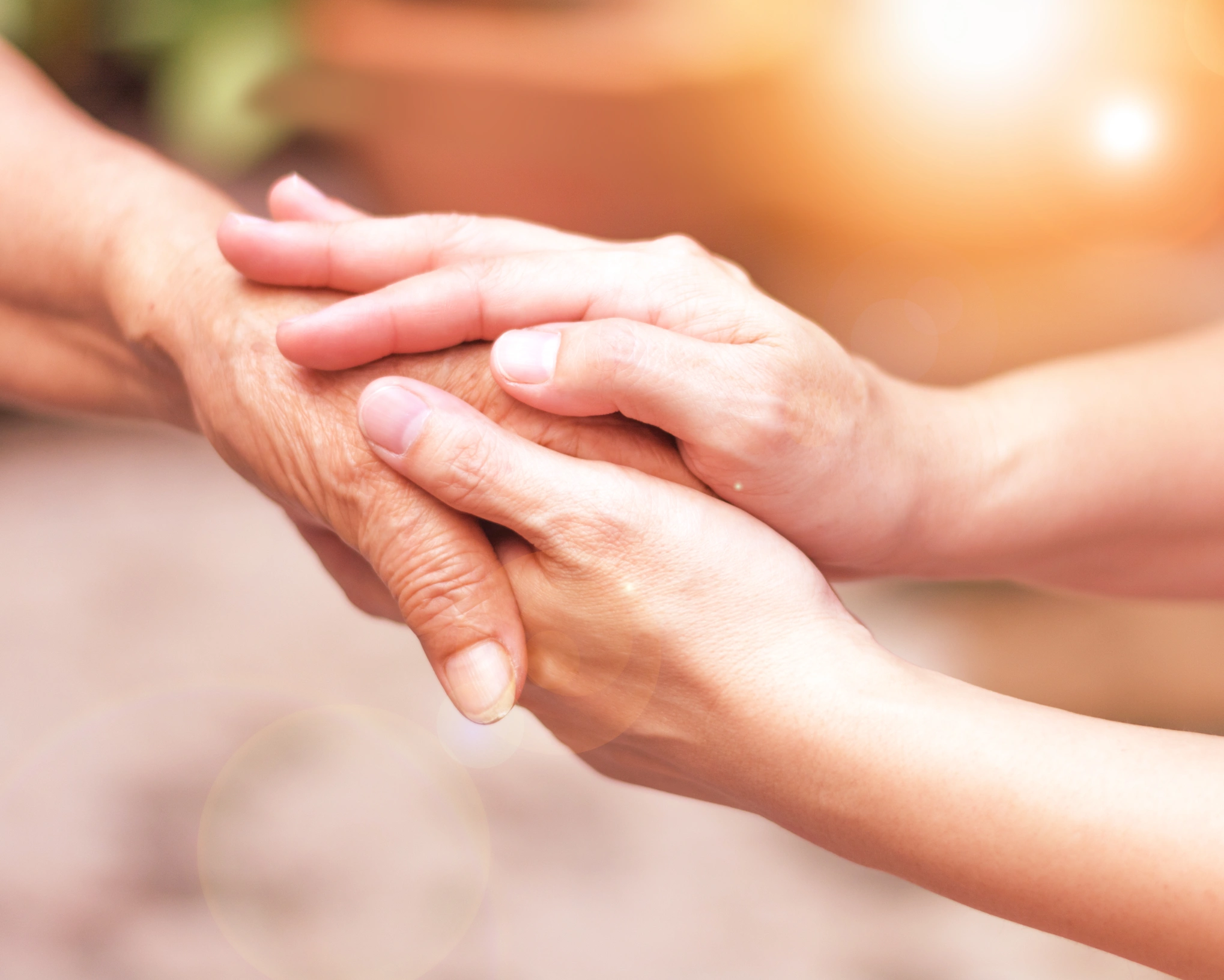 A senior lady holding hand of young woman, showing love and support.