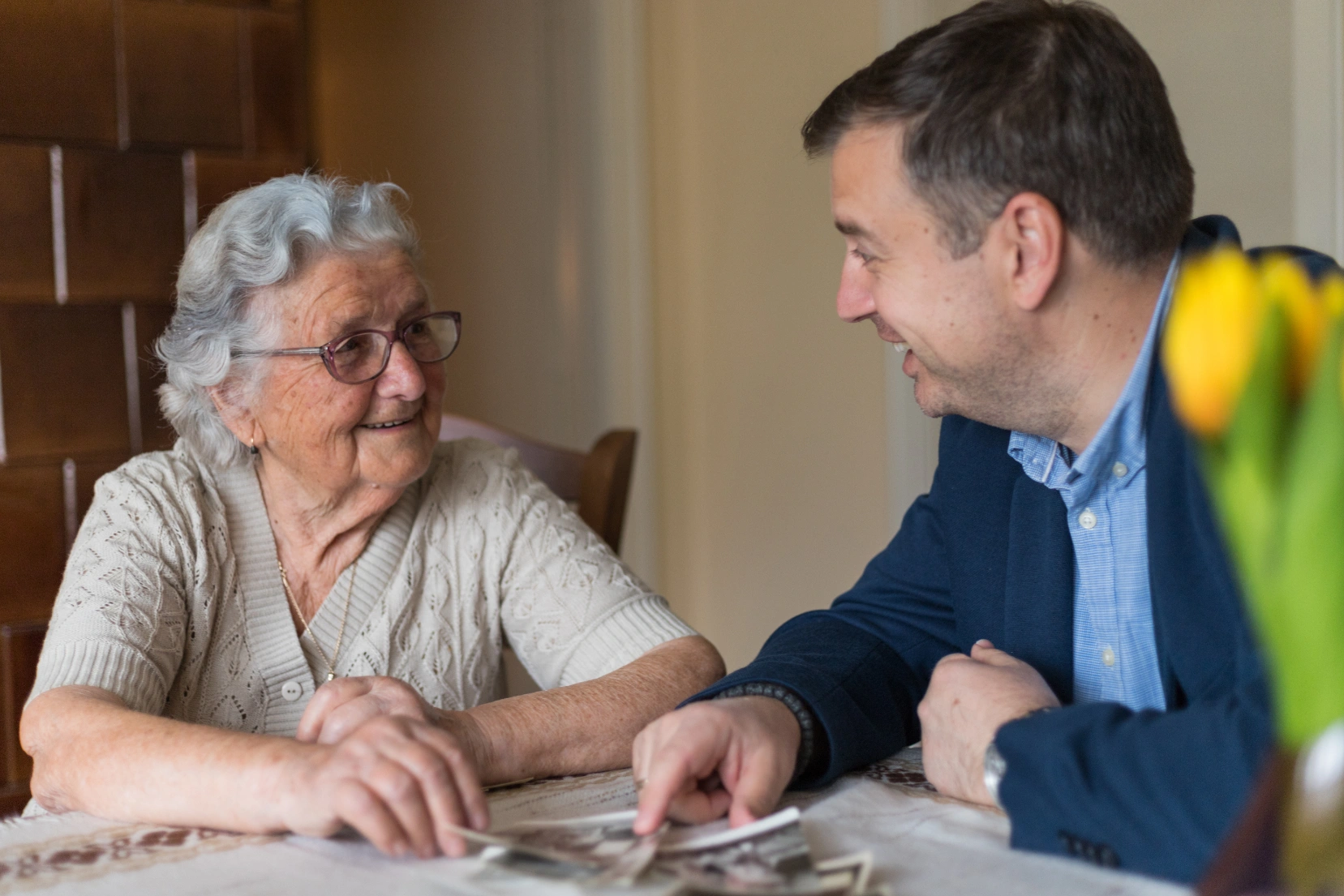 An elderly woman sitting with a man at a table, having a discussion.